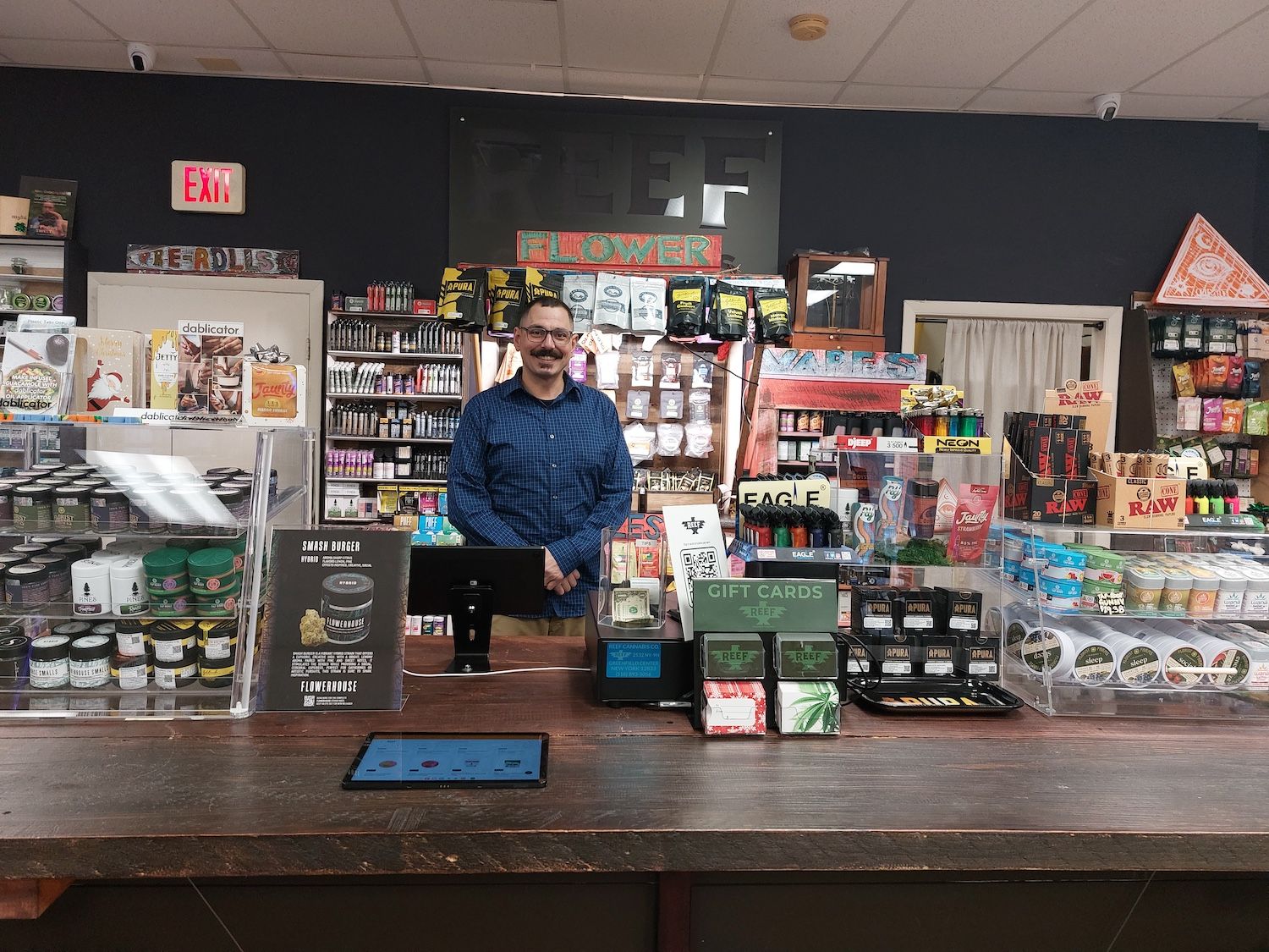 man standing behind the counter at reef cannabis company