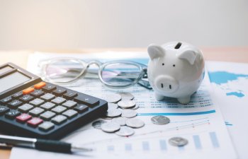 Calculator with text Tax Saving. Calculator, Piggy Bank, coins, business graph and pen on wooden table."Concept saving money for finance accounting