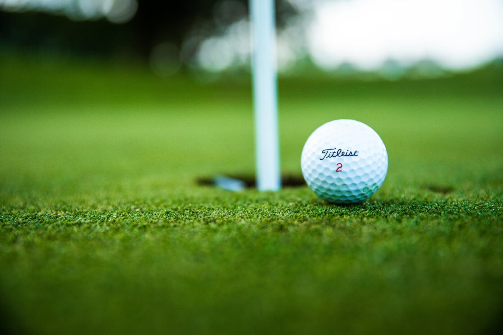 golf ball right next to hole close up