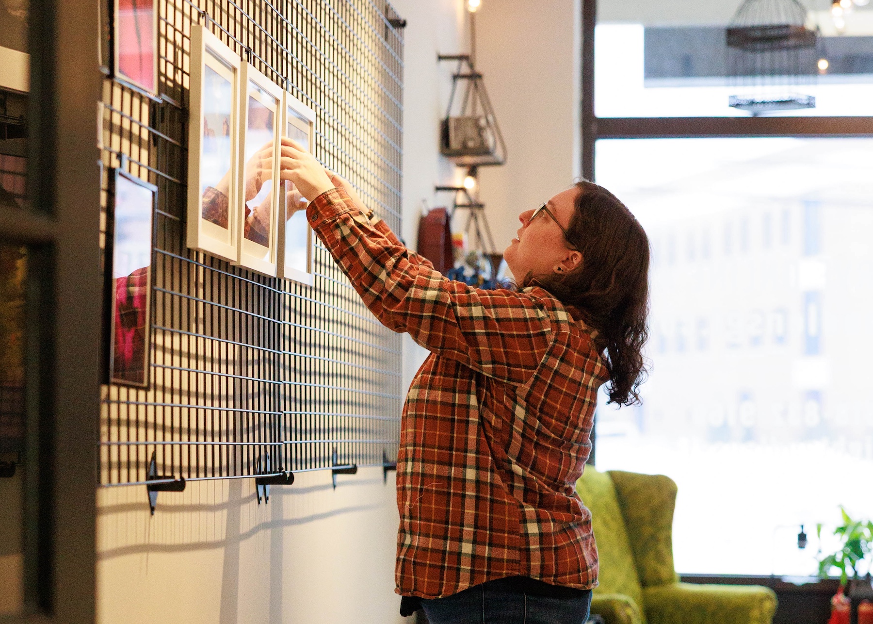 Jess Keller hanging a photo on the wall at the light & lens studio