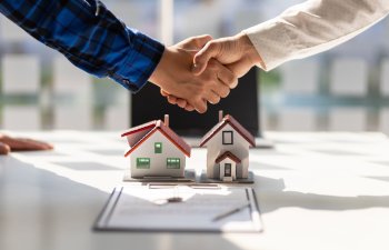 Real estate agents shake hands after the signing of the contract agreement is complete.