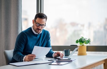 Busy elegant bearded adult company director, checking the company finances, at the office.