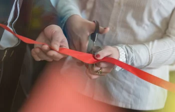 two people cutting a large ribbon close up
