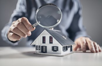 House with ith man holding magnifying glass concept for home inspection or searching for a new house