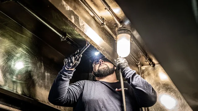 man cleaning kitching exhaust in dark room