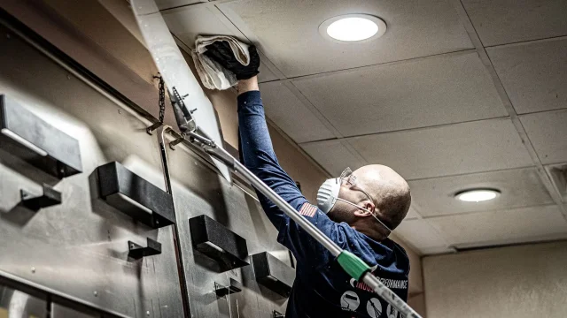 Person cleaning ceiling with cloth