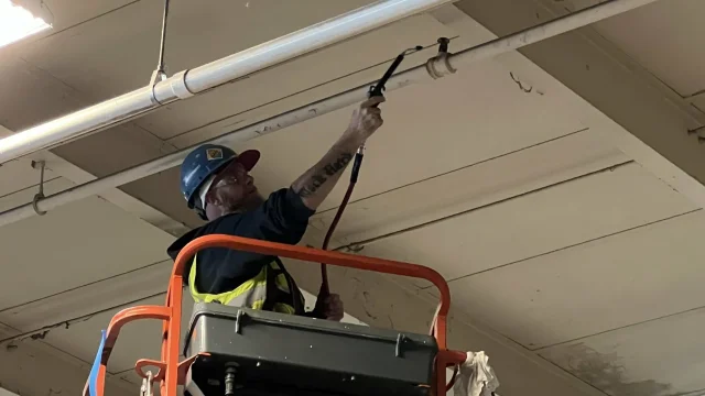 person working on pipes on the ceiling