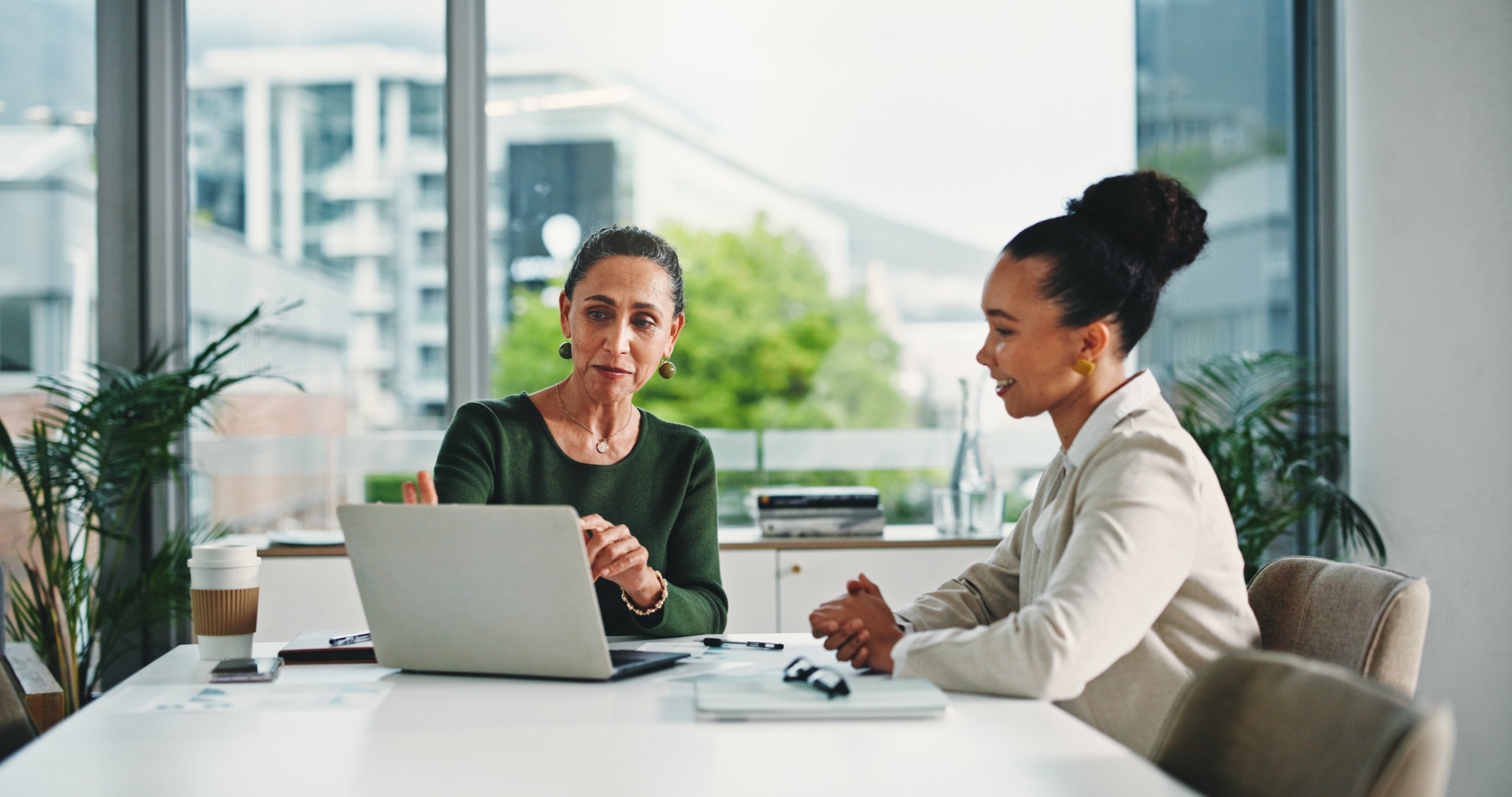 Computer, discussion and business women in office with feedback on corporate performance review. Meeting, laptop and female hr manager with employee for advice on career evaluation in workplace.