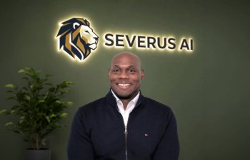 Smiling man in front of logo.